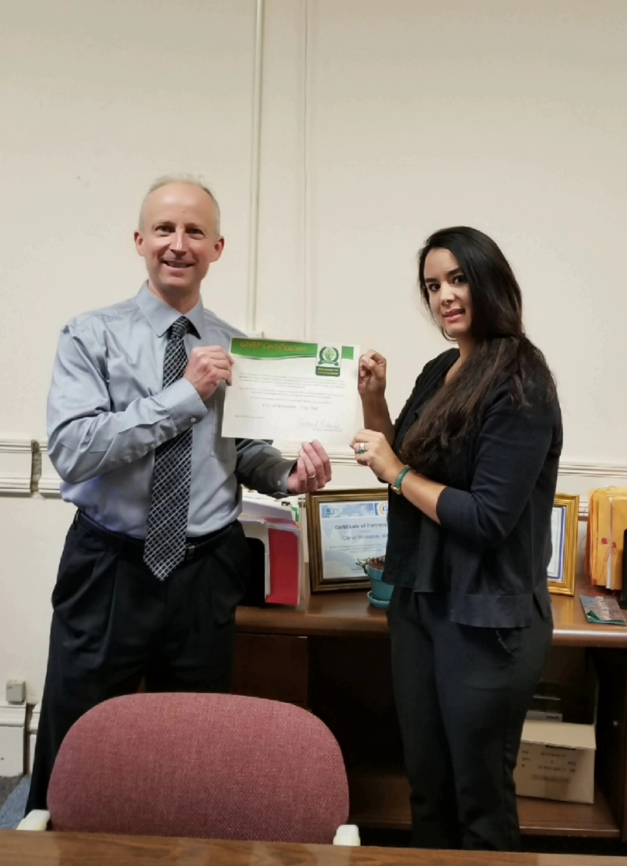 John Odell, Director of Worcester Energy and Asset Management Division, and Diana Gallego, owner and General Manager of BestPro Cleaning, holding up a Worcester City Hall’s Green and Healthy Building Certificate